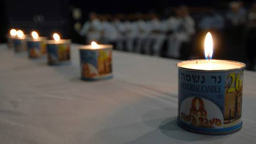 Several lit yahrzeit candles lined up on a table